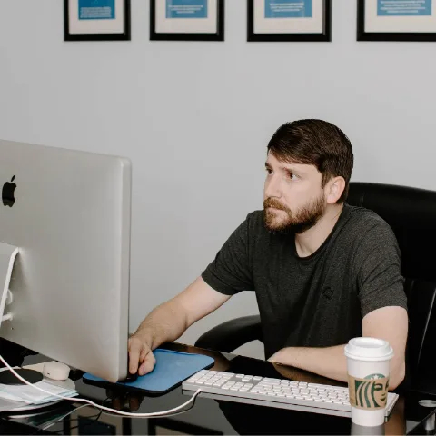 A team member at an iMac beneath a row of framed prints
