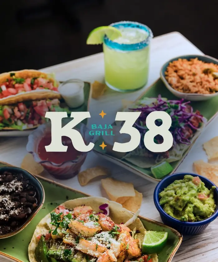The K38 Baja Grill logo over a spread of tacos, chips, guacamole and a margarita