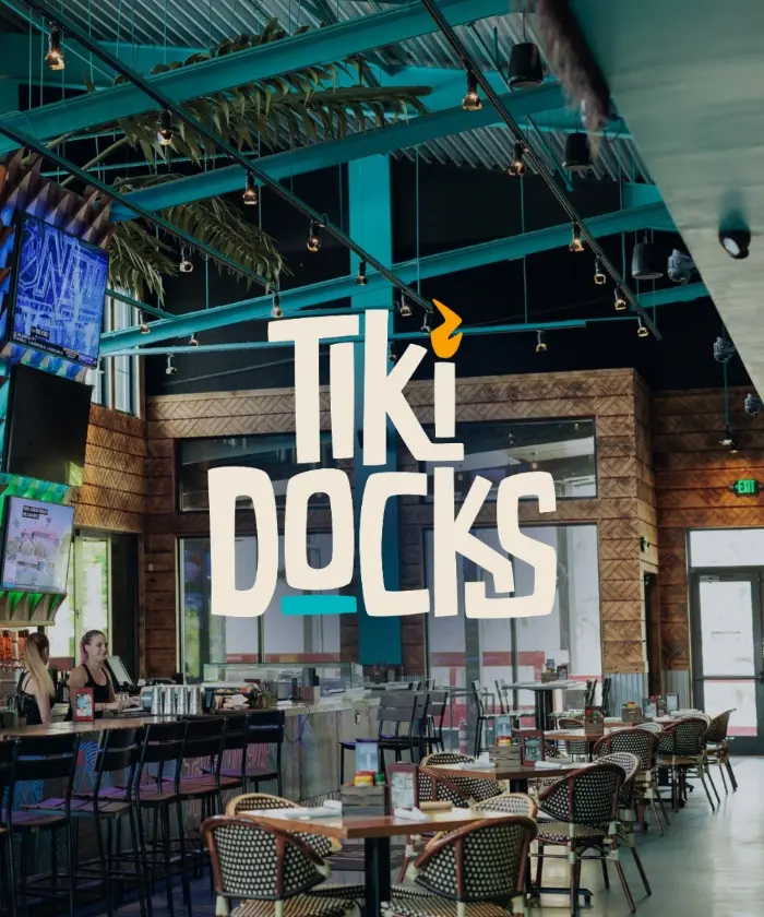 The Tiki Docks logo over the restaurant's open dining room with palm-draped rafters